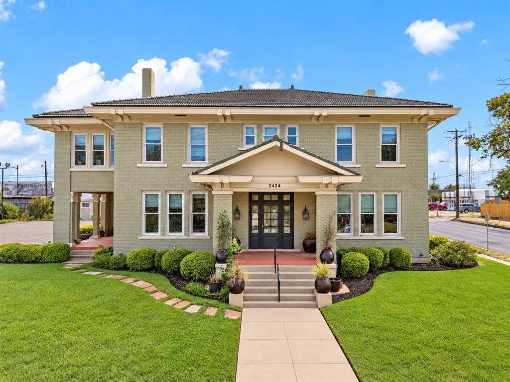2424 Austin Avenue, Waco, TX 76701 Brick exterior with a prominent front entrance, featuring a covered porch, multiple windows, and a landscaped front yard with a walkway
