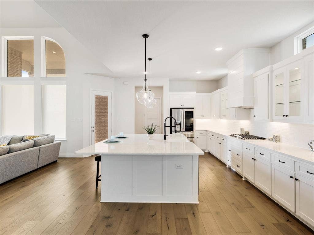 508 N Pecan Parkway, Northlake, TX 76247 Gourmet kitchen with white cabinetry, stainless steel appliances, a large center island with counter seating, and wood-finish flooring
