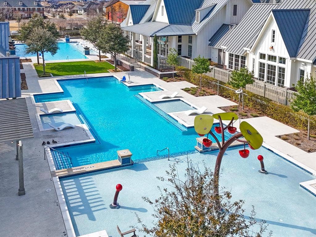 508 N Pecan Parkway, Northlake, TX 76247 Expansive aquatic area featuring multiple pools, a splash pad with interactive water features, sun shelf lounging areas, and surrounding hardscaping
