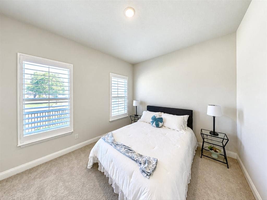508 N Pecan Parkway, Northlake, TX 76247 Bright bedroom with neutral wall paint, two windows featuring white plantation shutters, and light-colored carpeting