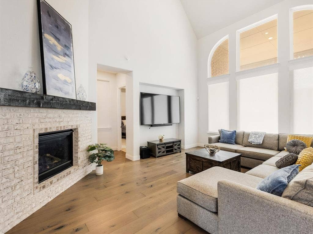 508 N Pecan Parkway, Northlake, TX 76247 Vaulted ceilings, wood-finish flooring, and a fireplace with a light brick surround
