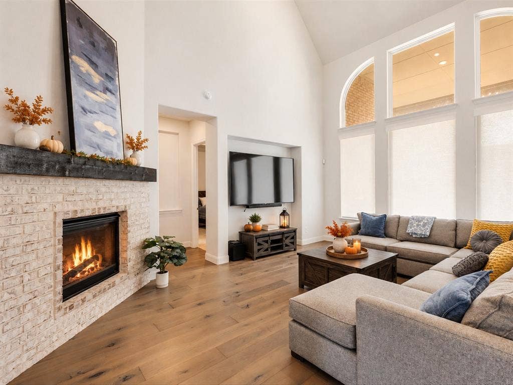 508 N Pecan Parkway, Northlake, TX 76247 Vaulted ceiling living room featuring a stone-clad fireplace with a wood mantel, wood-finish flooring, and multiple large windows