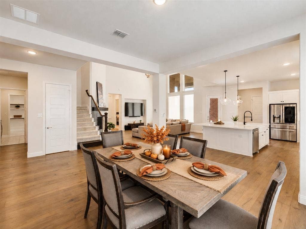 508 N Pecan Parkway, Northlake, TX 76247 Open-concept floor plan featuring wood-finish flooring, a white kitchen island with pendant lighting, and a staircase with a dark wood handrail