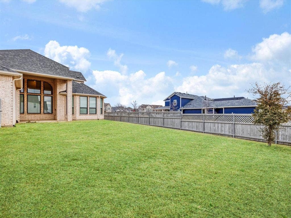 508 N Pecan Parkway, Northlake, TX 76247 Expansive green lawn, light brick exterior, dark-toned roof, multiple large windows, and a wood privacy fence