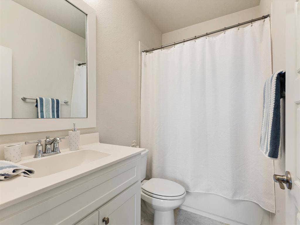 508 N Pecan Parkway, Northlake, TX 76247 White vanity with integrated sink, chrome faucet, framed mirror, and a full-size bathtub with shower