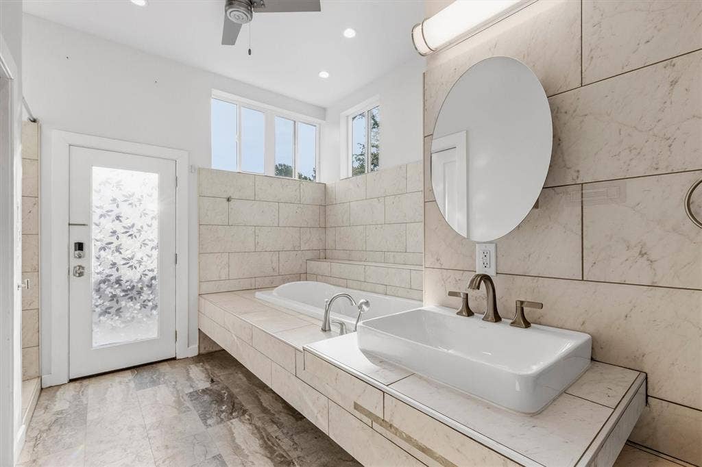 Spacious bathroom featuring a vessel sink, an integrated soaking tub, recessed lighting, and a ceiling fan