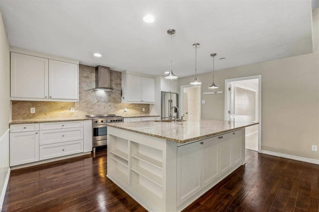 Kitchen featuring an expansive island with a stone countertop, white shaker cabinetry, stainless steel range with matching hood, and wood-finish flooring