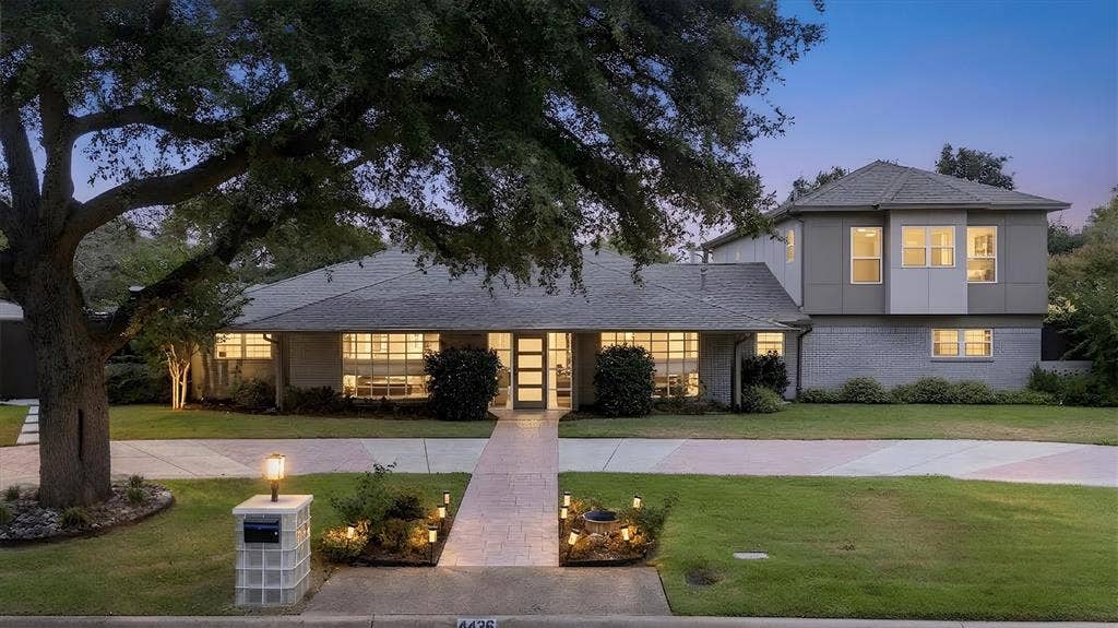 Expansive front yard with mature trees, manicured lawn, and a paved walkway leading to the entrance