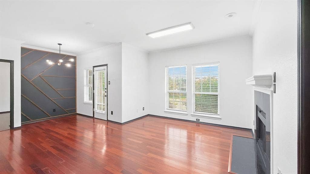 1700 Amelia Court, #126, Plano, TX 75075 Hardwood flooring throughout, a decorative accent wall with geometric wood trim, a modern chandelier, and a fireplace with a mantel