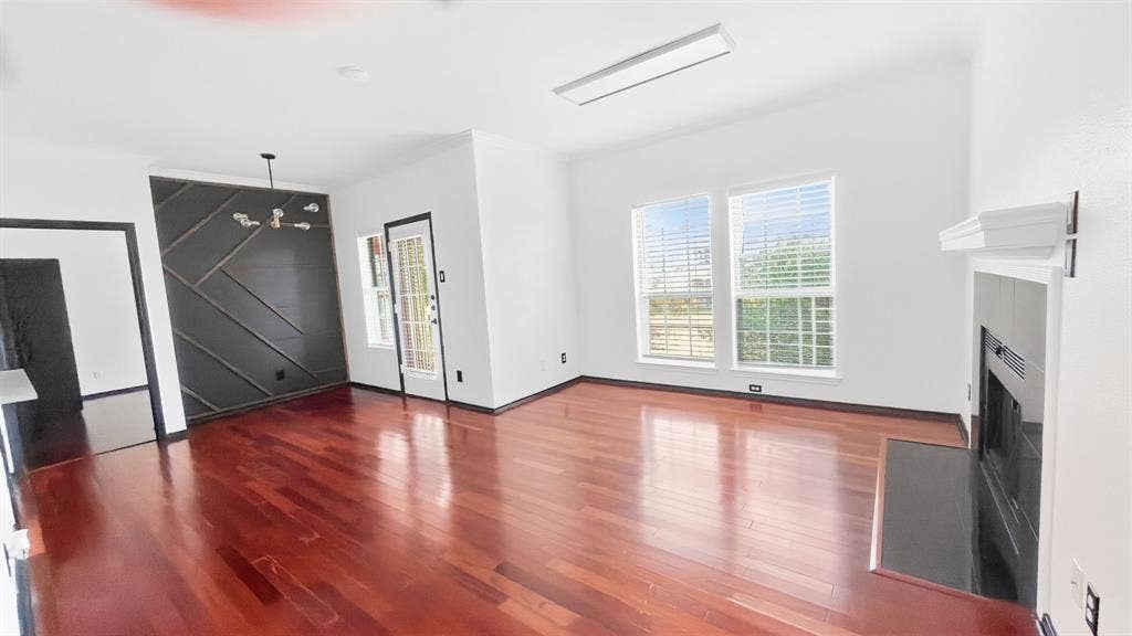 1700 Amelia Court, #126, Plano, TX 75075 Hardwood flooring throughout, contemporary accent wall, modern chandelier, fireplace with hearth, and multiple windows