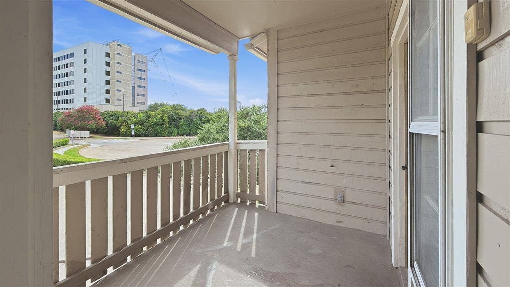 1700 Amelia Court, #126, Plano, TX 75075 Private balcony with a concrete floor, wood railing, and an exterior sliding glass door