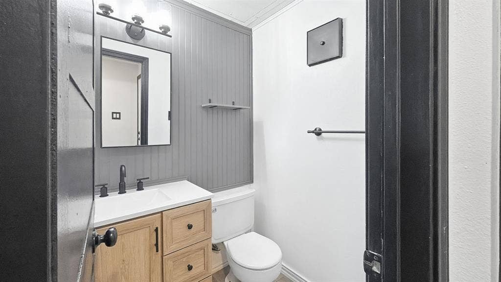 1700 Amelia Court, #126, Plano, TX 75075 Wood-finish vanity with white countertop, matte black faucet, and rectangular mirror