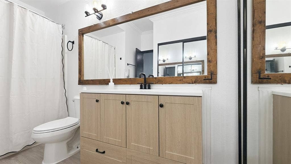 1700 Amelia Court, #126, Plano, TX 75075 Wood-finish vanity with a light countertop, complemented by a large wood-framed mirror