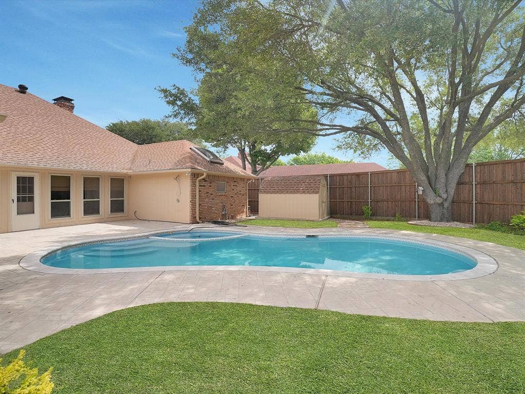 1304 Carriage Creek Drive, DeSoto, TX 75115 In-ground swimming pool with integrated spa, concrete decking, mature tree, manicured lawn, and privacy fence
