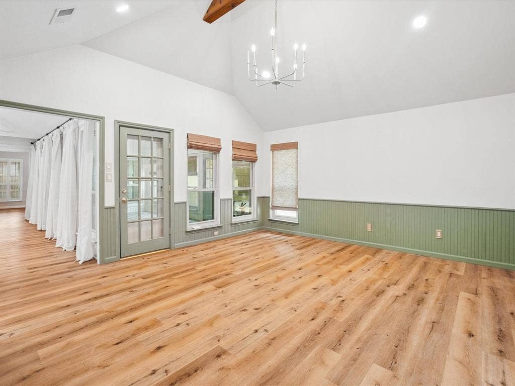 1304 Carriage Creek Drive, DeSoto, TX 75115 Vaulted ceiling with an exposed wood beam, wood-finish flooring, two large windows, a glass-paned door, and beadboard wainscoting