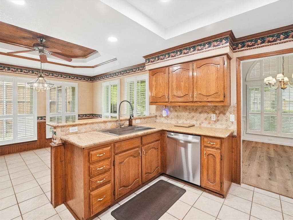 1304 Carriage Creek Drive, DeSoto, TX 75115 Kitchen featuring wood cabinetry, light-toned stone countertops, tile backsplash, and stainless steel appliances