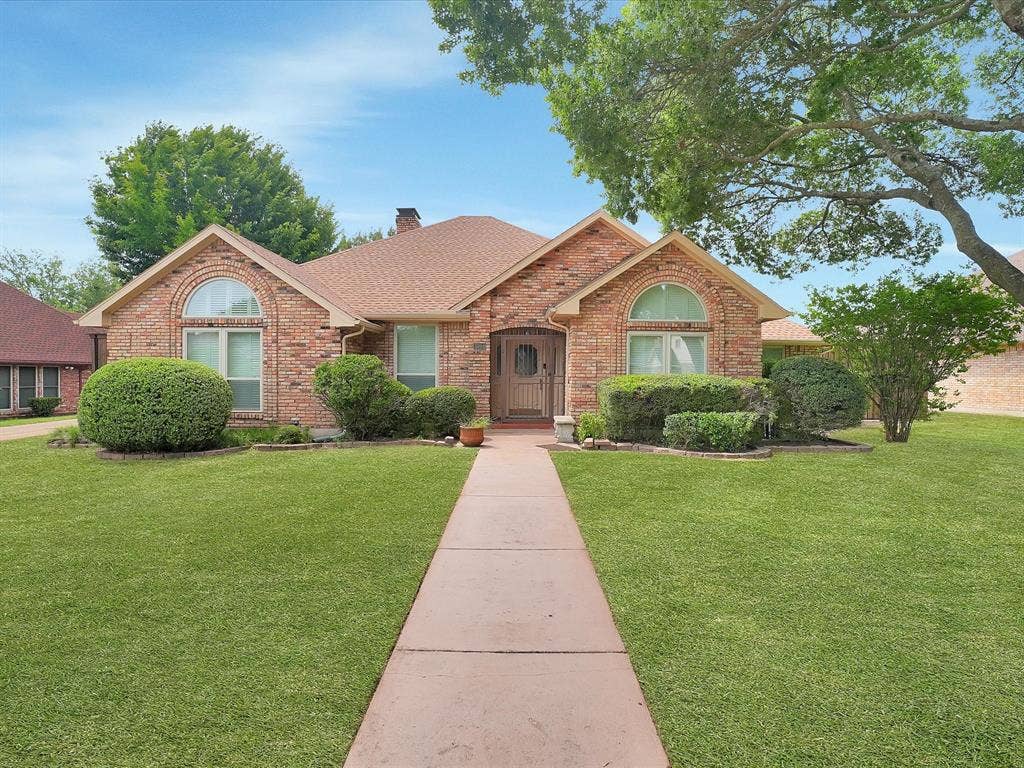 1304 Carriage Creek Drive, DeSoto, TX 75115 Brick exterior with arched windows, gabled rooflines, and a concrete pathway leading to the entrance