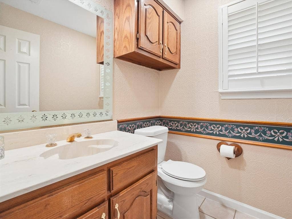 1304 Carriage Creek Drive, DeSoto, TX 75115 Wood-finish vanity with a light-toned countertop, under-mount sink, and brass-tone faucet