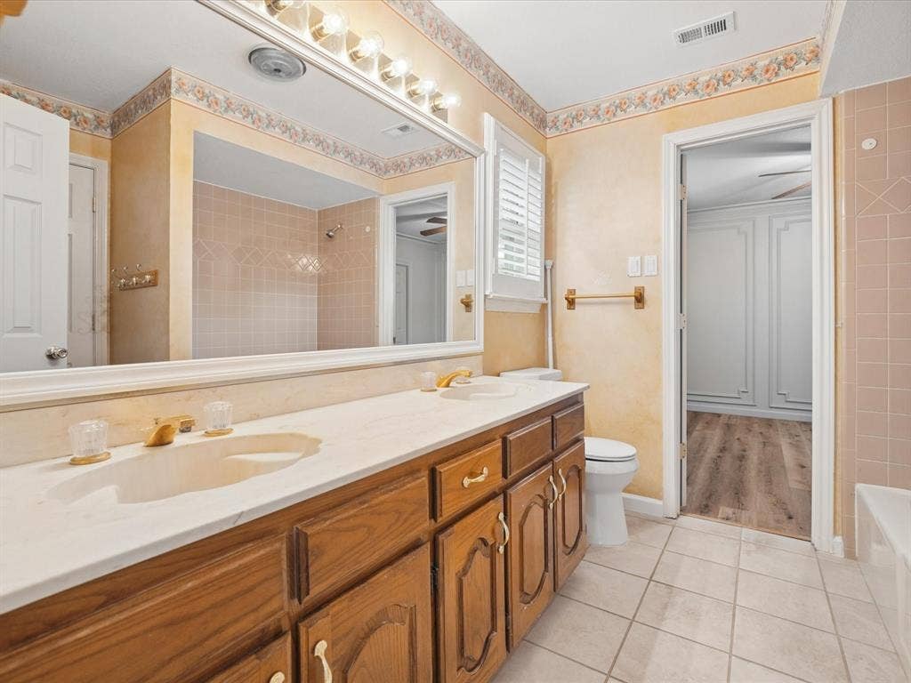 1304 Carriage Creek Drive, DeSoto, TX 75115 Double vanity with integrated sinks, wood-finish cabinetry, and a full-width mirror