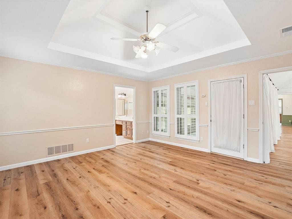 1304 Carriage Creek Drive, DeSoto, TX 75115 Tray ceiling with a ceiling fan, wood-finish flooring, white window shutters, and chair rail molding