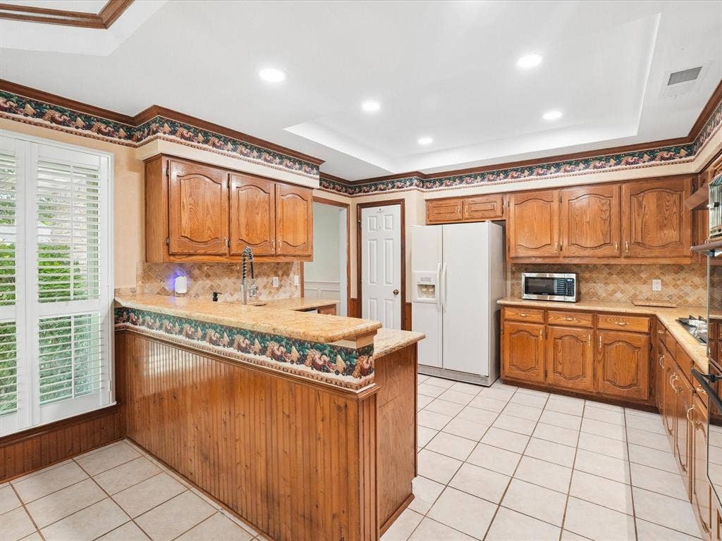 1304 Carriage Creek Drive, DeSoto, TX 75115 Kitchen featuring wood cabinetry, light-toned countertops, white tile flooring, and recessed ceiling lighting