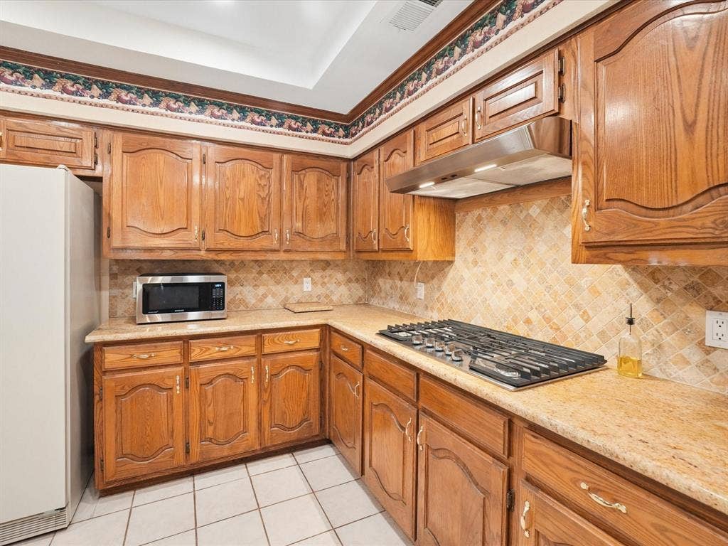 1304 Carriage Creek Drive, DeSoto, TX 75115 Recessed ceiling with an overhead light fixture, wood-finish cabinetry, tile flooring, and a built-in gas cooktop