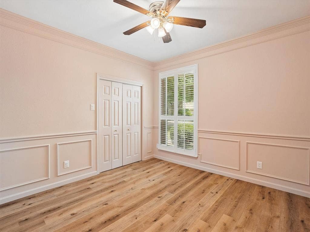 1304 Carriage Creek Drive, DeSoto, TX 75115 Wood-finish flooring, crown molding, wainscoting, bi-fold closet doors, and a ceiling fan with light fixture