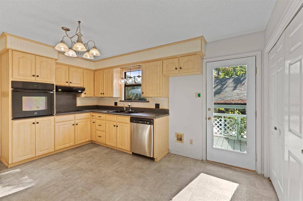 1656 Pineview Lane, Hideaway, TX 75771 L-shaped kitchen featuring wood cabinetry, built-in oven, stainless steel dishwasher, and a glass-paned door