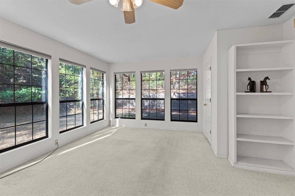 1656 Pineview Lane, Hideaway, TX 75771 Wall-to-wall carpeting, multiple large windows with grids, built-in shelving, ceiling fan, and white painted walls