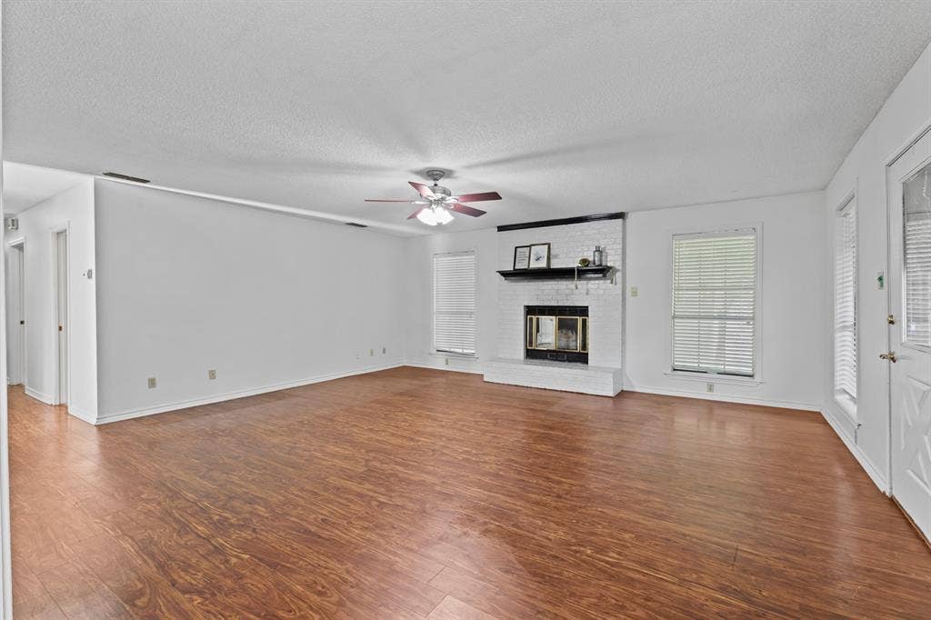 1656 Pineview Lane, Hideaway, TX 75771 Expansive living area featuring wood-finish flooring, a white brick fireplace with a dark mantel, and multiple windows