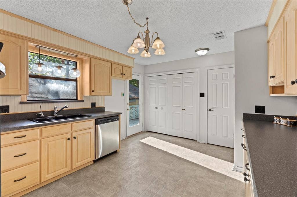 1656 Pineview Lane, Hideaway, TX 75771 Light wood-finish cabinetry with dark hardware, stainless steel dishwasher, dark countertops, and a double-basin sink
