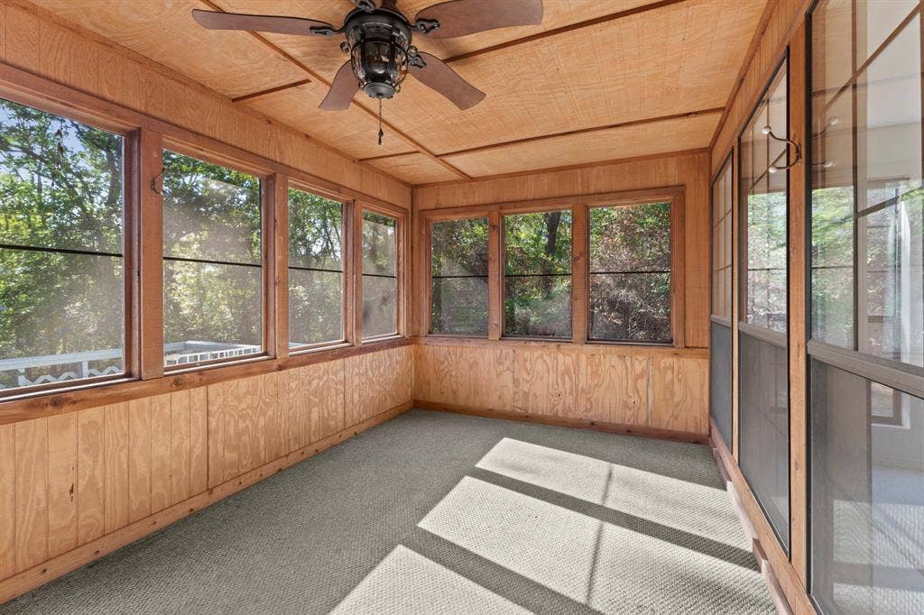 1656 Pineview Lane, Hideaway, TX 75771 Sunroom featuring wood paneling, multiple windows, a ceiling fan, and carpeted flooring