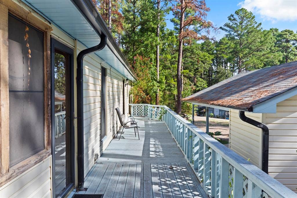 1656 Pineview Lane, Hideaway, TX 75771 Expansive wood deck with lattice railing, multiple exterior doors, and full-length gutters