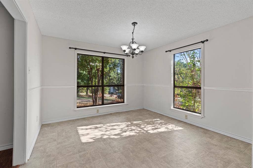 1656 Pineview Lane, Hideaway, TX 75771 Recessed lighting with a ceiling-mounted chandelier, paired with two large windows, white wall paneling, and tile flooring