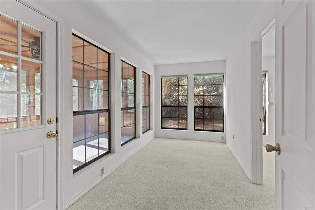 1656 Pineview Lane, Hideaway, TX 75771 Crisp white walls, neutral carpeting, multiple windows with black grilles, and a white paneled door with brass hardware