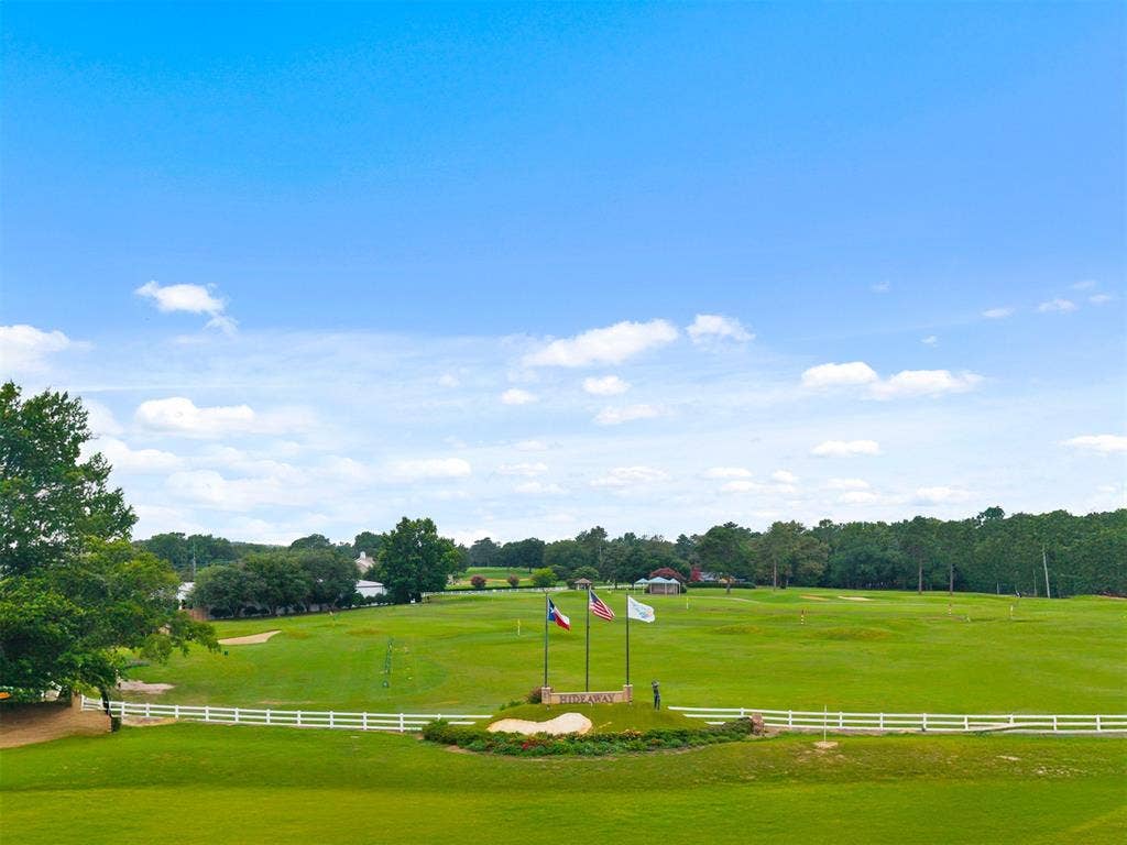 1656 Pineview Lane, Hideaway, TX 75771 Expansive golf course setting featuring manicured greens, a decorative monument with flags, and a white fence border