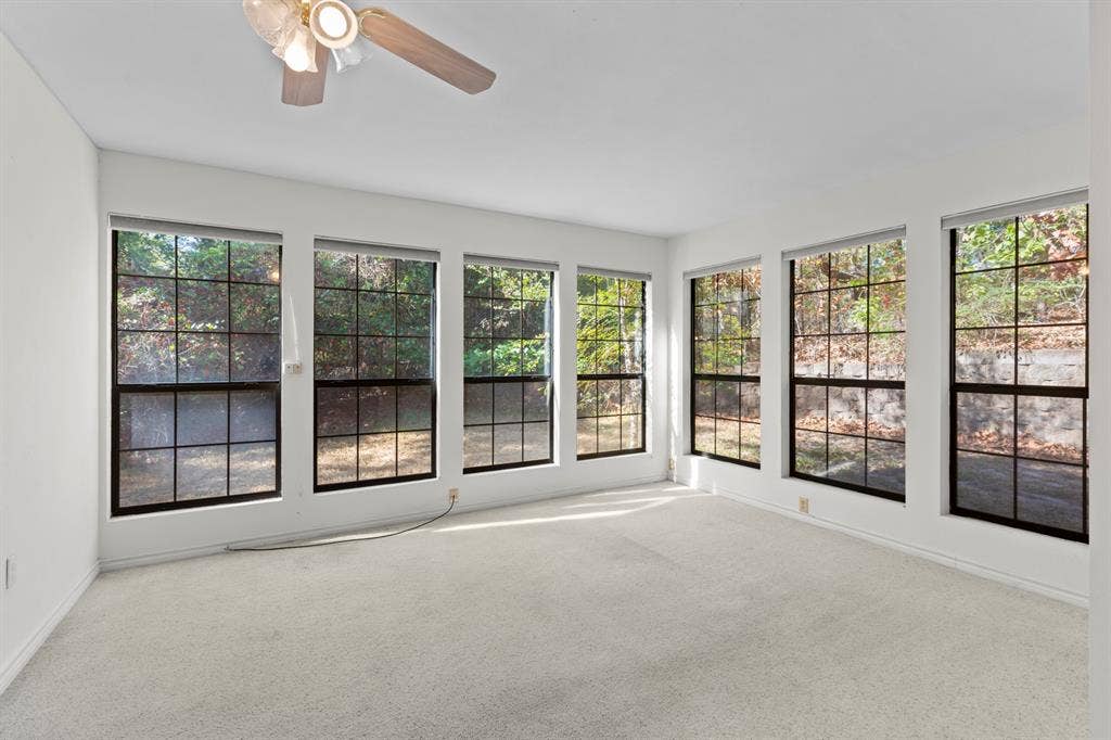1656 Pineview Lane, Hideaway, TX 75771 Recessed windows with black grilles, white walls, light-colored carpeting, and a ceiling fan with integrated lighting