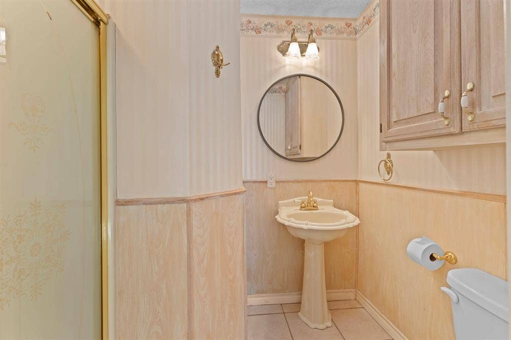 1656 Pineview Lane, Hideaway, TX 75771 Pedestal sink, wall-mounted vanity light, round mirror, built-in cabinetry, and wainscoting