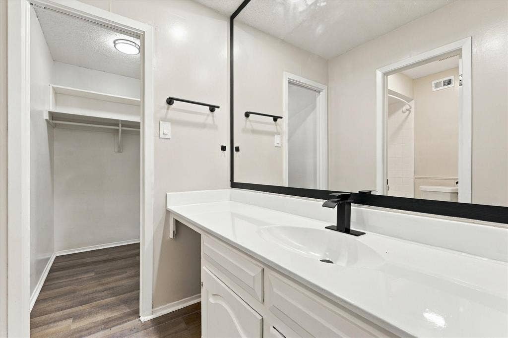 White vanity with integrated sink, black single-handle faucet, and oversized mirror