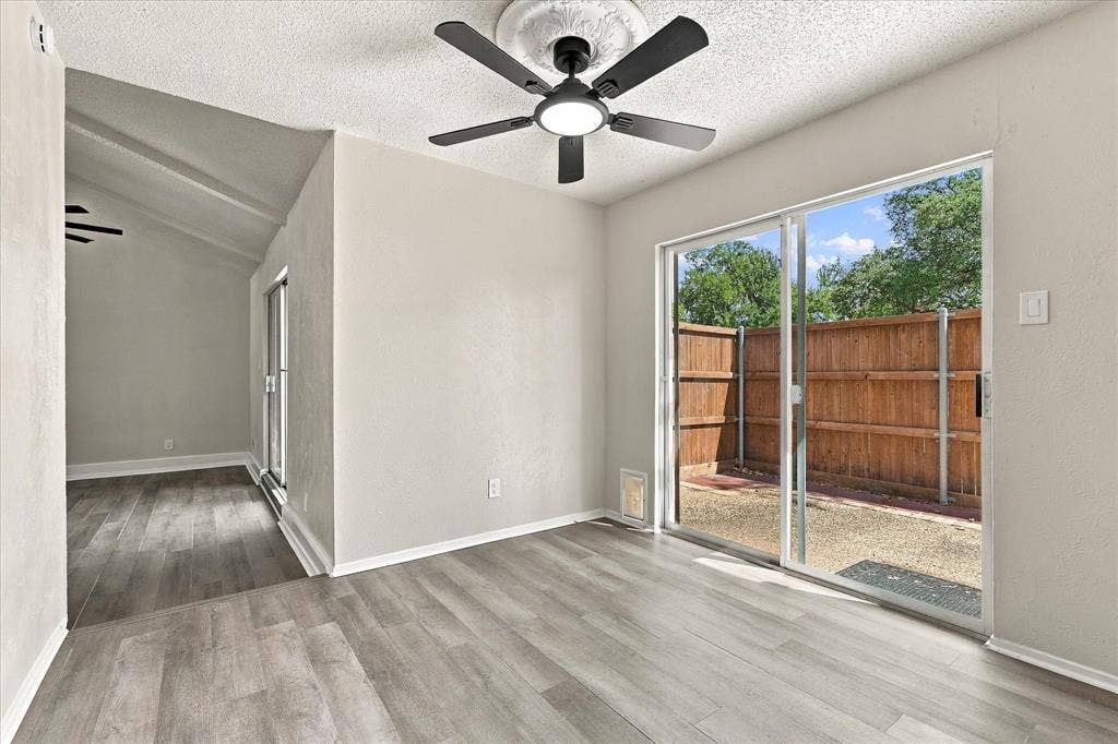 Wood-finish flooring throughout, with a matte black ceiling fan