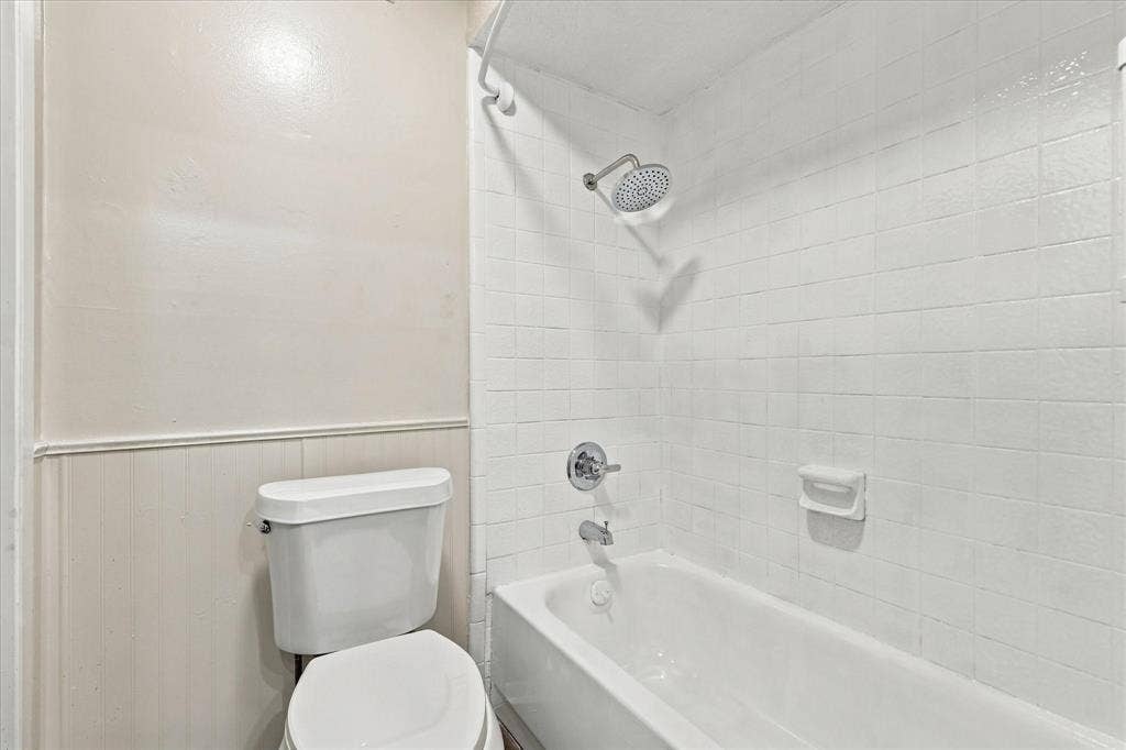 Bathtub with subway tile surround, chrome showerhead, and matching fixtures