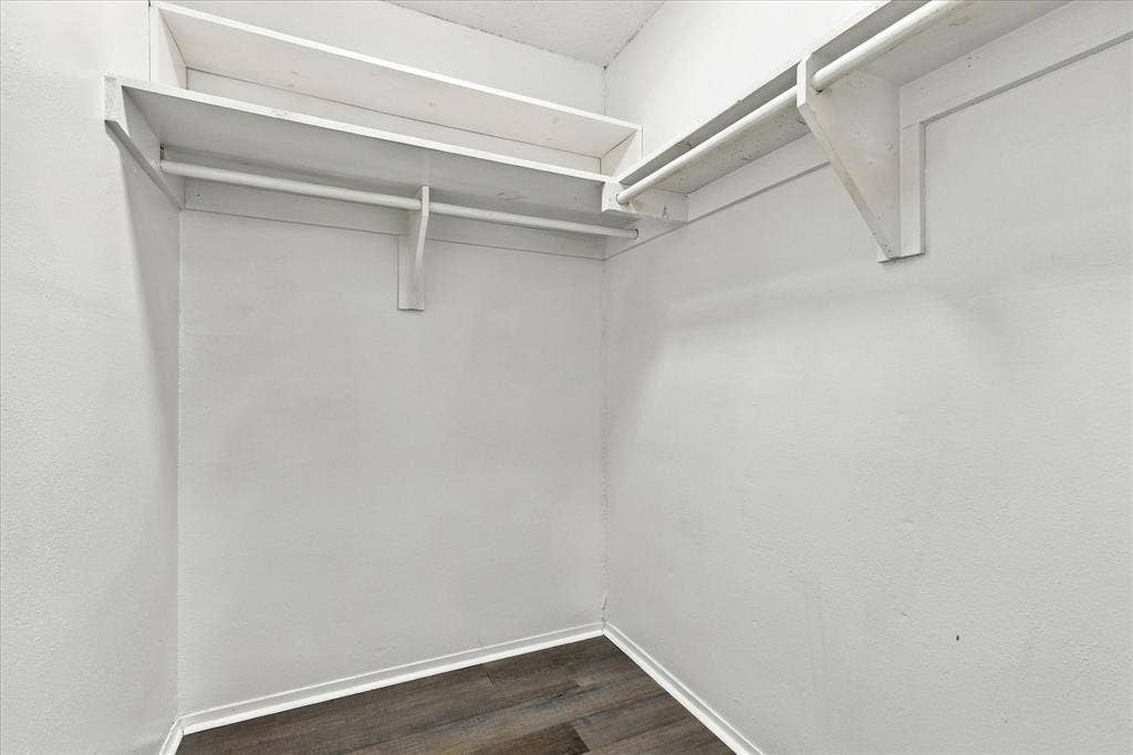White interior walls, multi-tier shelving, clothing rods, wood-finish flooring, and white trim