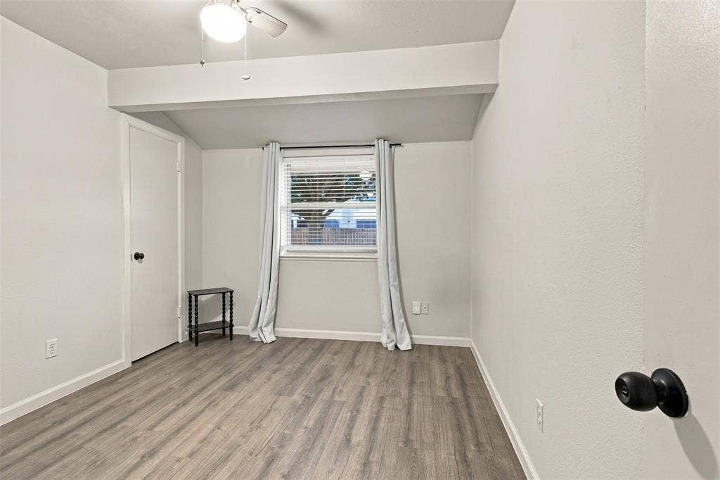 Wood-finish flooring, white walls, and a ceiling fan with integrated lighting