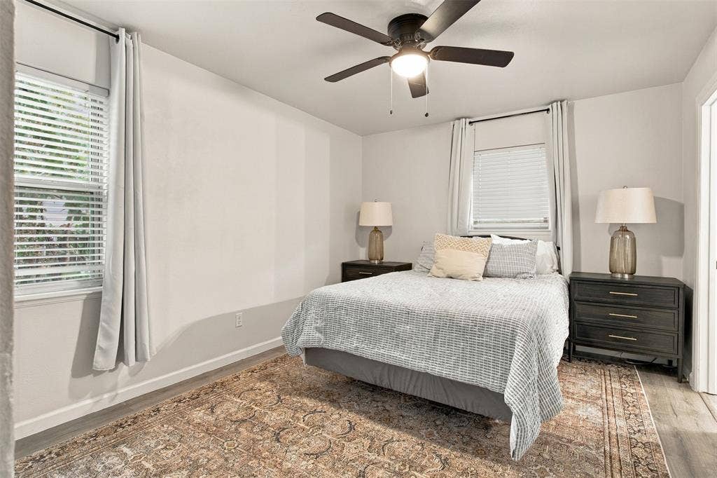 Recessed lighting, ceiling fan with integrated light, two windows with blinds, wood-finish flooring