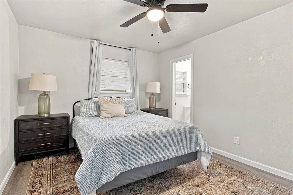 Recessed window with blinds, ceiling fan with integrated lighting, wood-finish flooring, and white painted walls