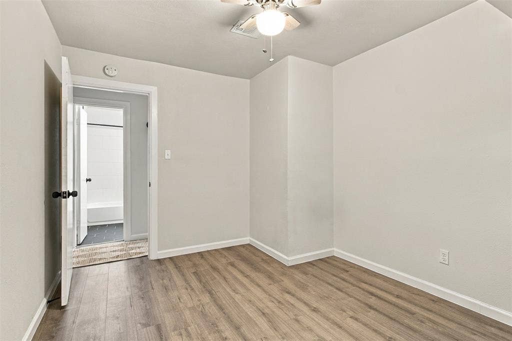 Wood-finish flooring, light-toned wall paint, and a ceiling fan with integrated lighting