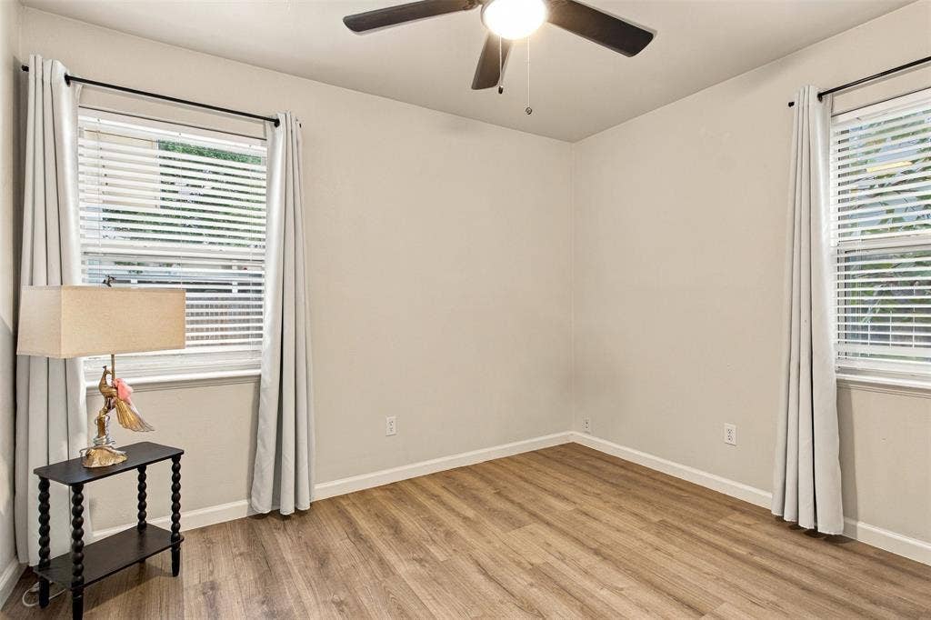 Wood-finish flooring, neutral wall tones, and a ceiling fan with integrated lighting