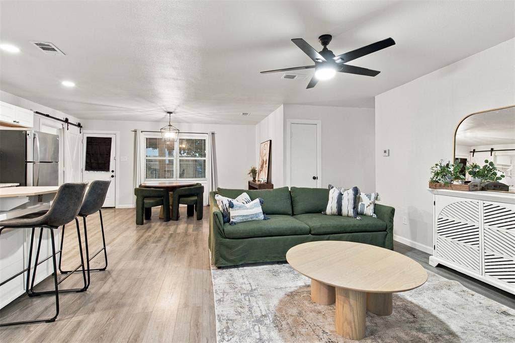 Open-concept living area featuring wood-finish flooring, a contemporary ceiling fan, and a light-filtering window