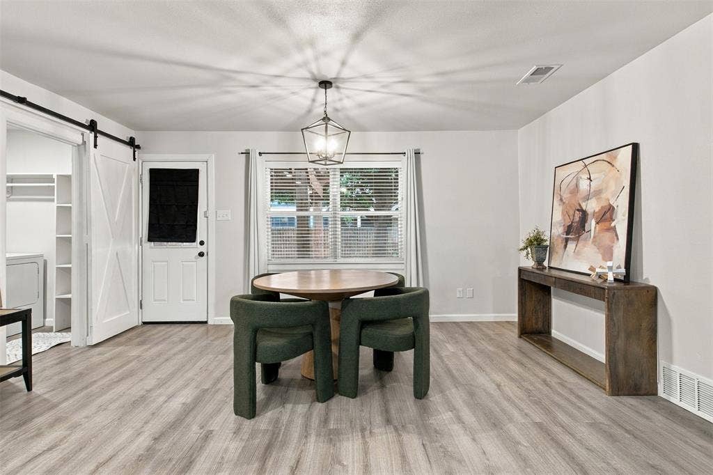 Wood-finish flooring throughout, white interior walls, and a modern geometric pendant light fixture