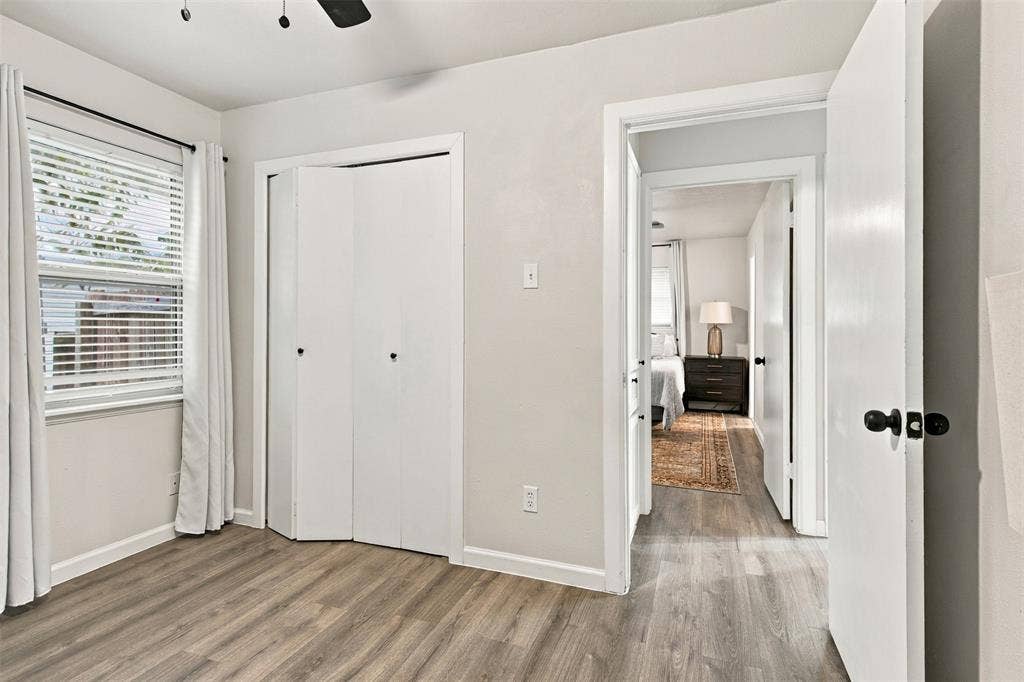 Wood-finish flooring, white walls, and a window with blinds
